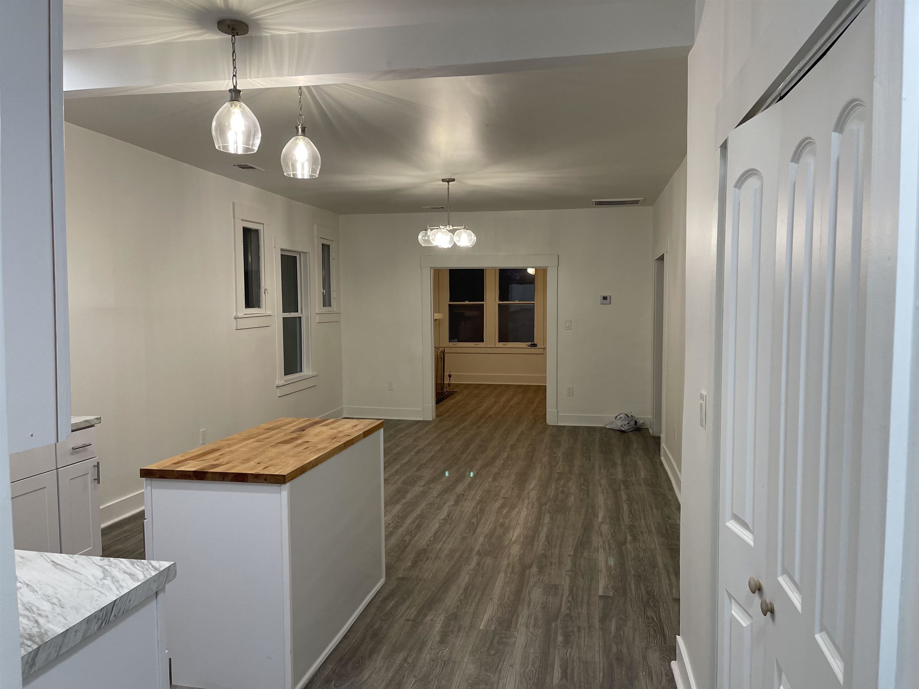 Kitchen with a center island, wooden counters, decorative light fixtures, dark hardwood / wood-style flooring, and white cabinetry