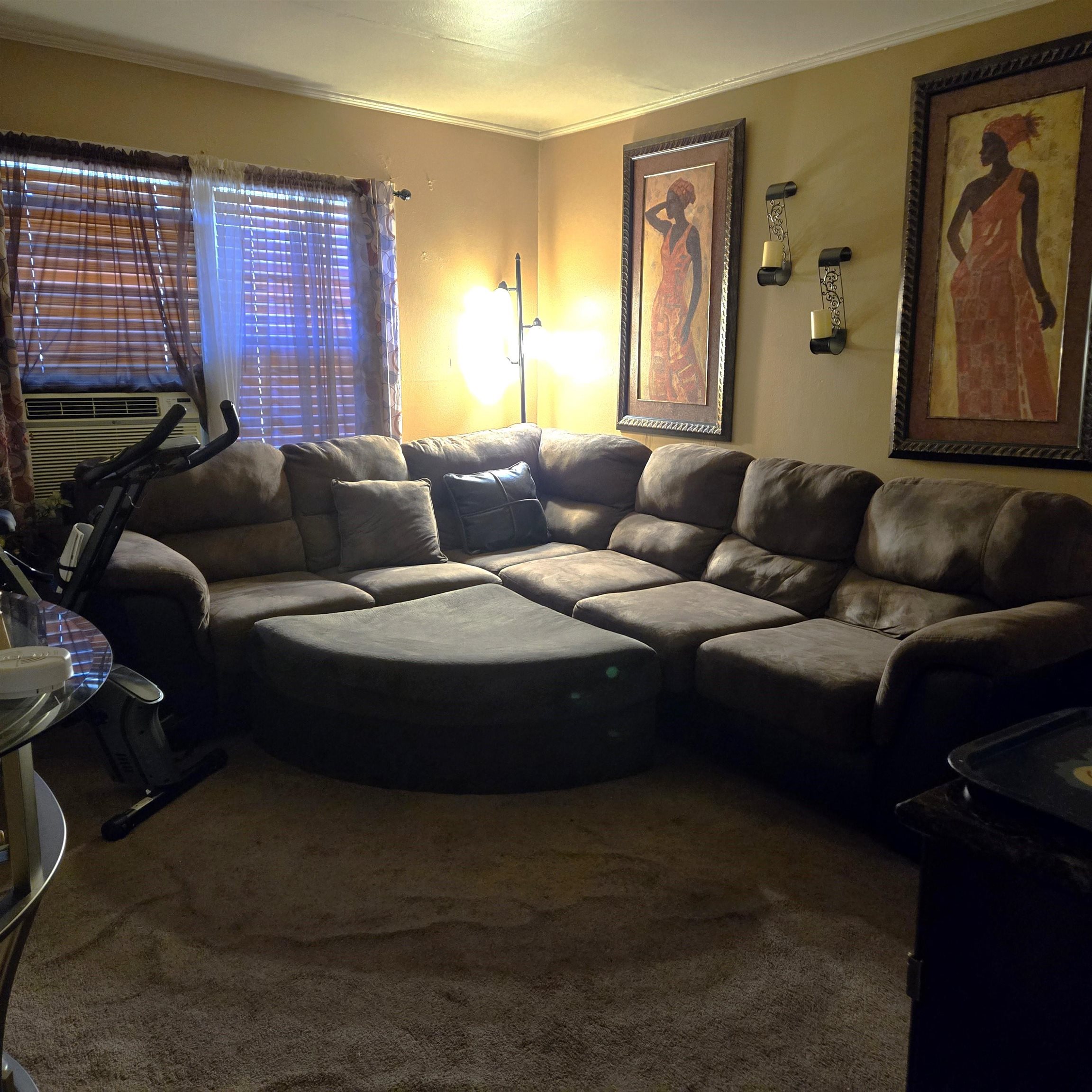 Carpeted living room with cooling unit and ornamental molding.