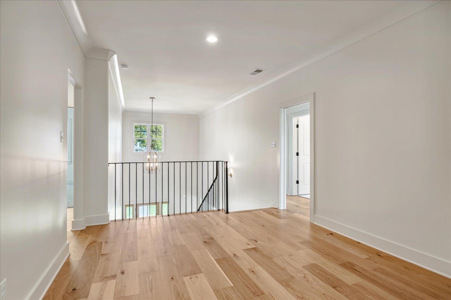 Empty room with light hardwood / wood-style flooring, an inviting chandelier, and crown molding