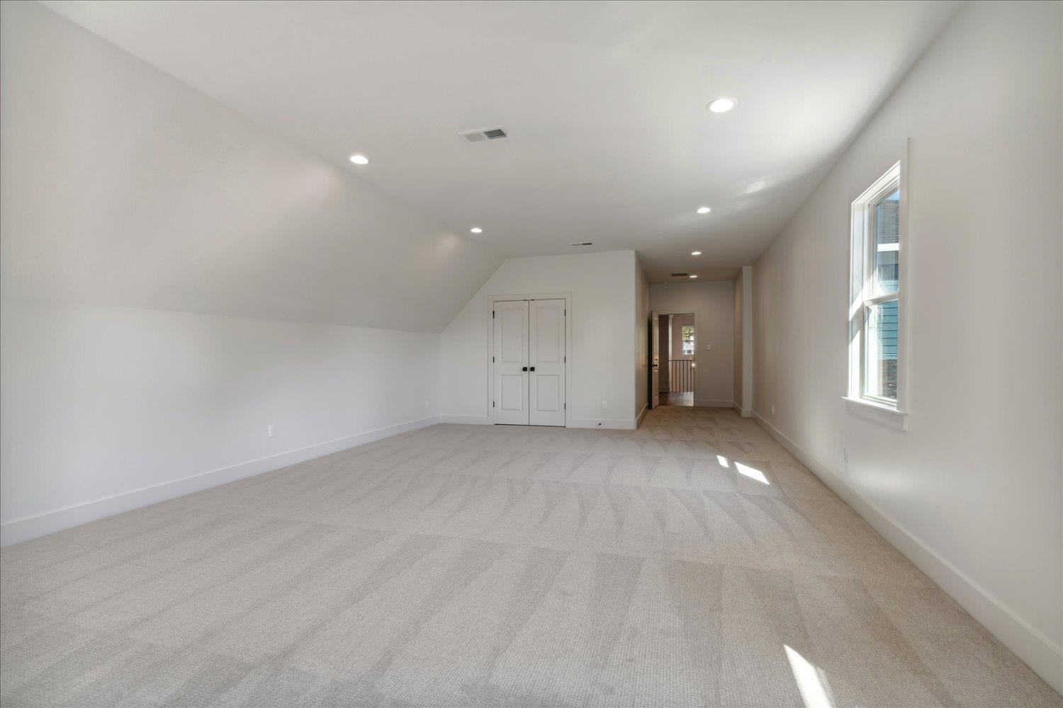 Additional living space featuring lofted ceiling and light colored carpet