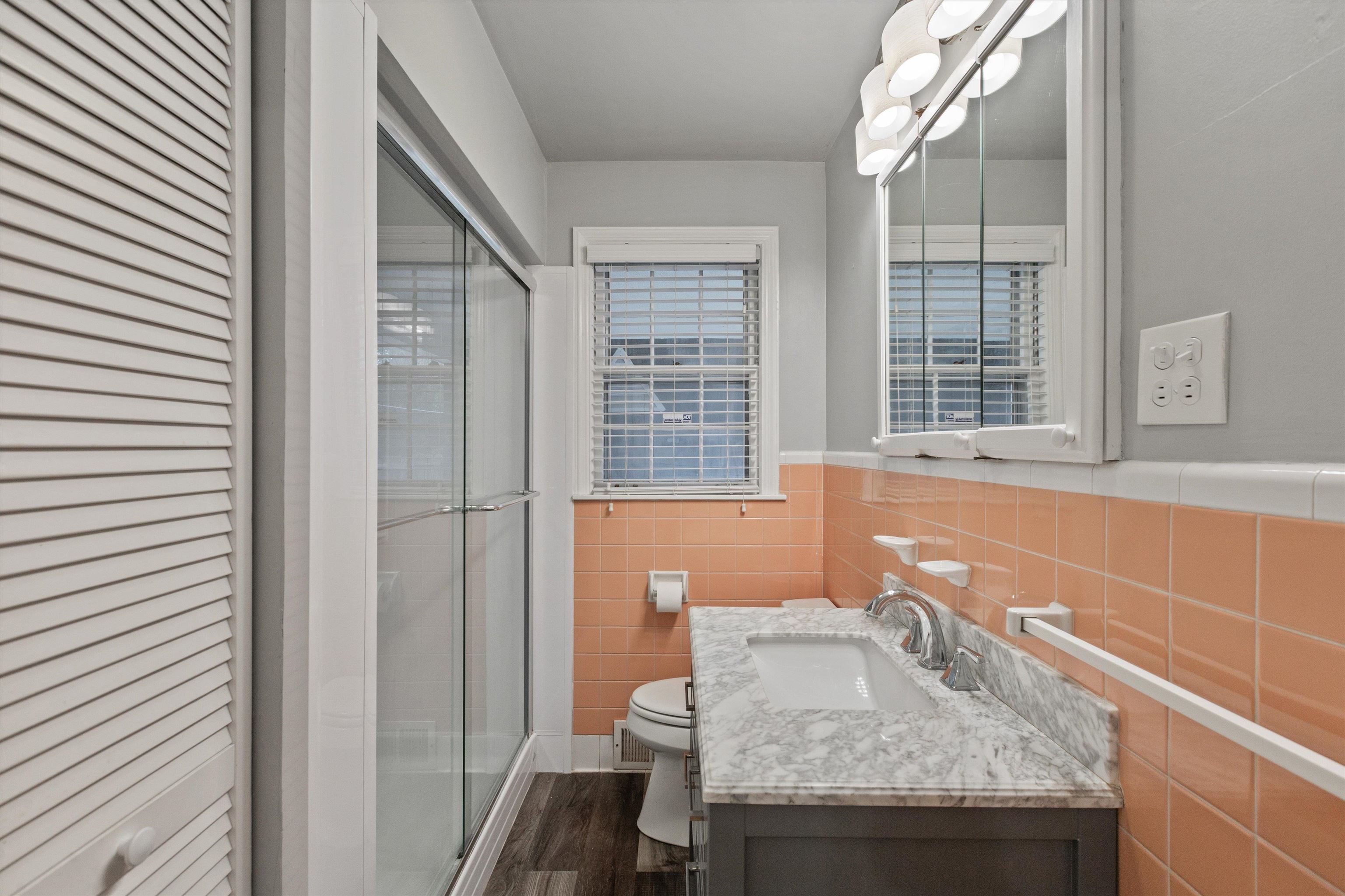 Bathroom with walk in shower, vanity, wood-type flooring, tile walls, and toilet