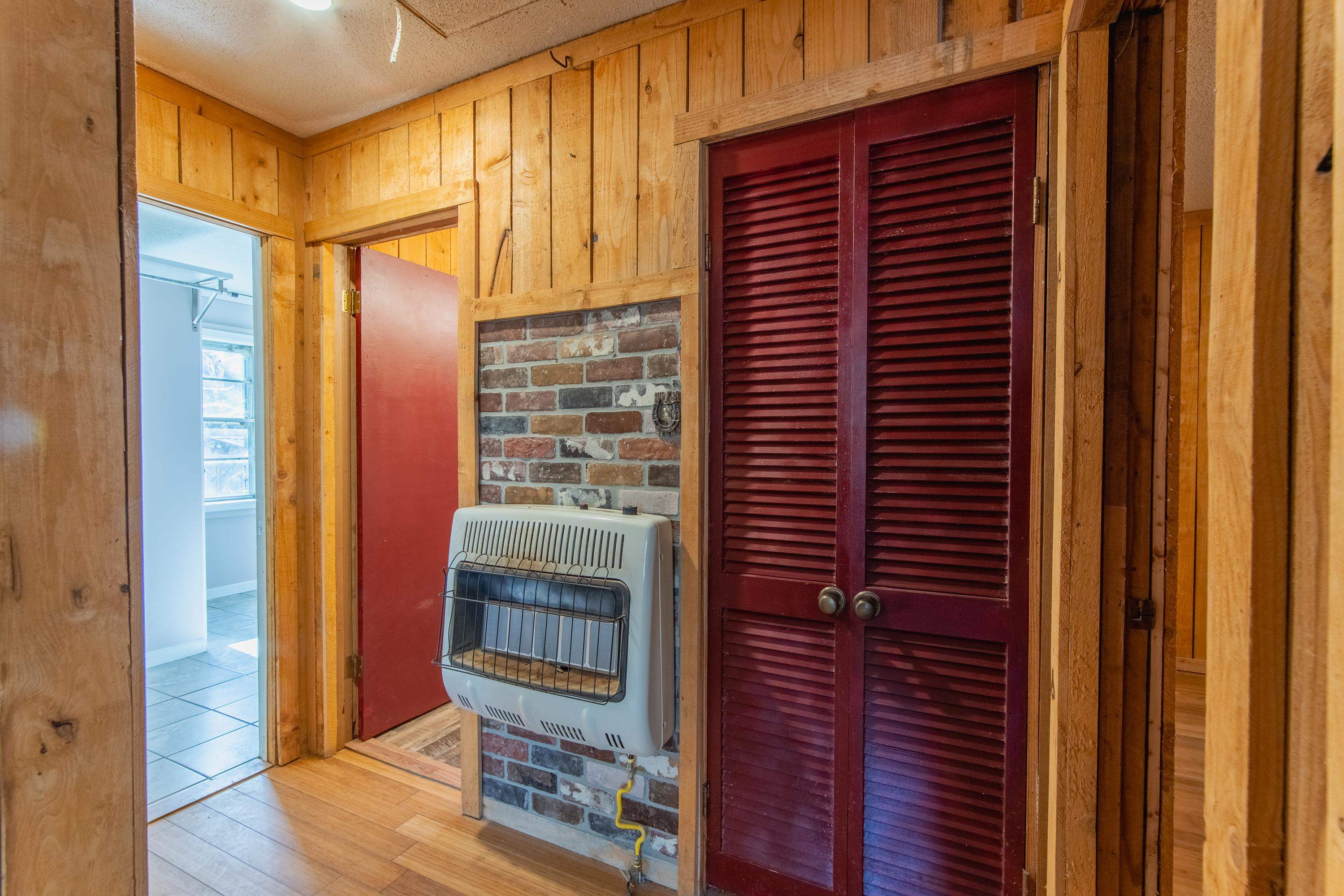 Corridor with wood walls, light hardwood / wood-style floors, brick wall, and heating unit