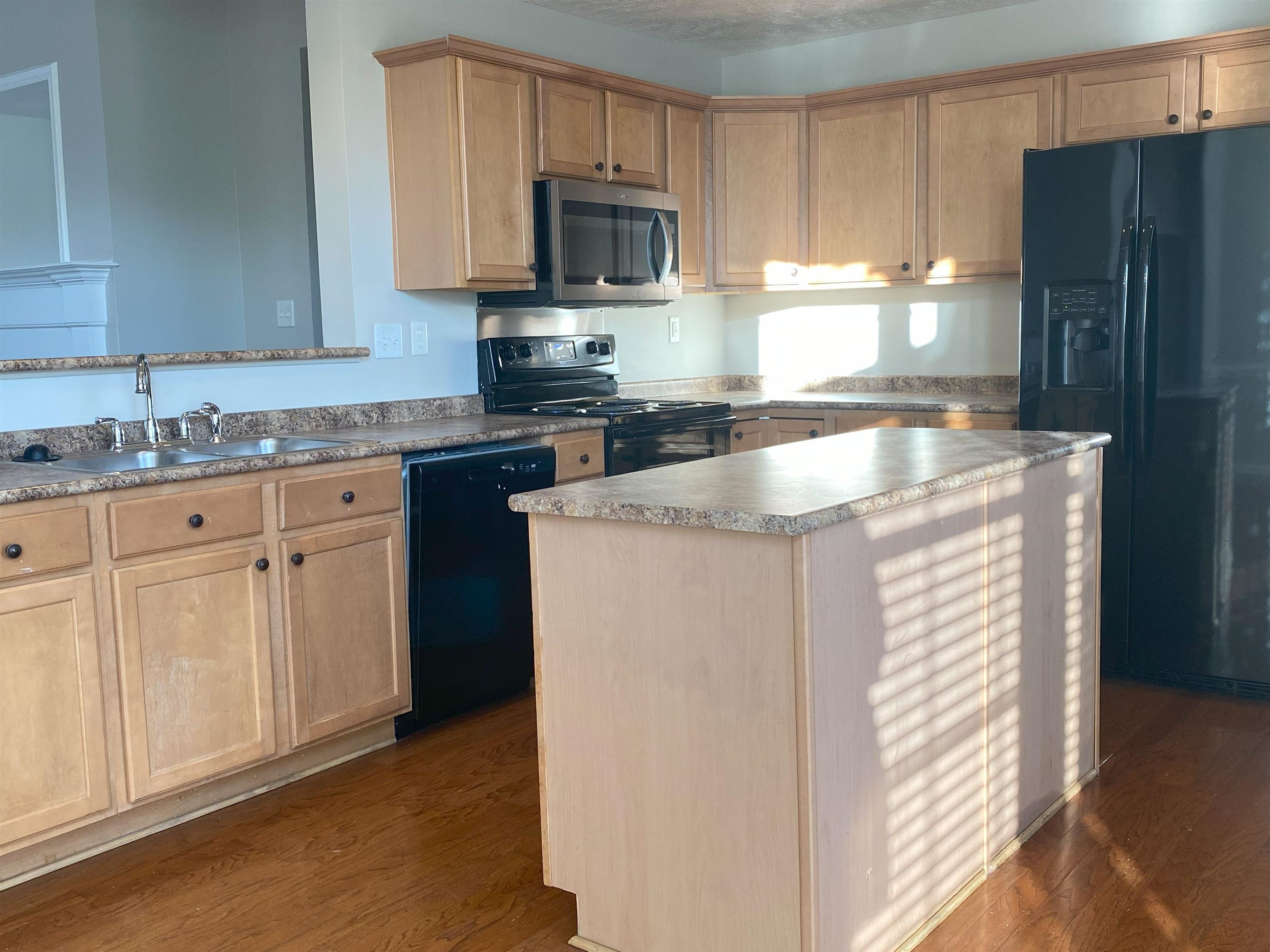 Kitchen featuring a center island, sink, dark hardwood / wood-style floors, and black appliances