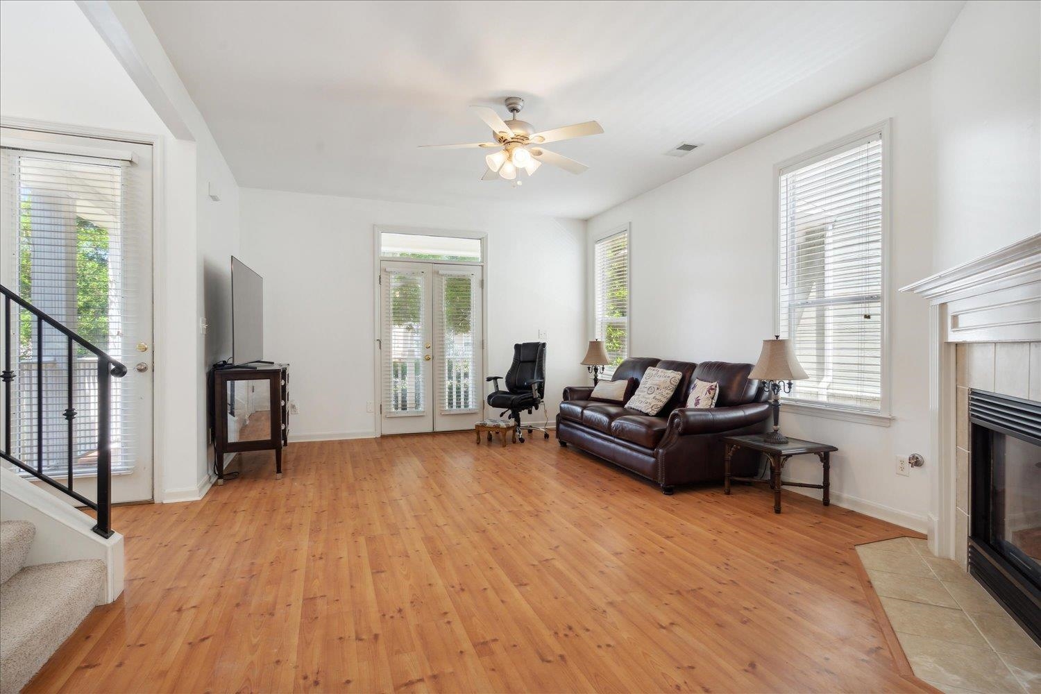 Living room with light hardwood / wood-style floors, a tile fireplace, and ceiling fan