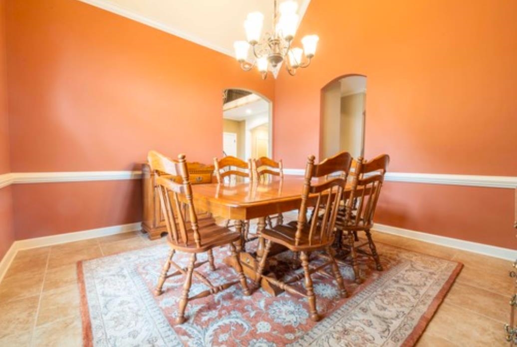 Dining area featuring tile patterned floors, ornamental molding, and a notable chandelier