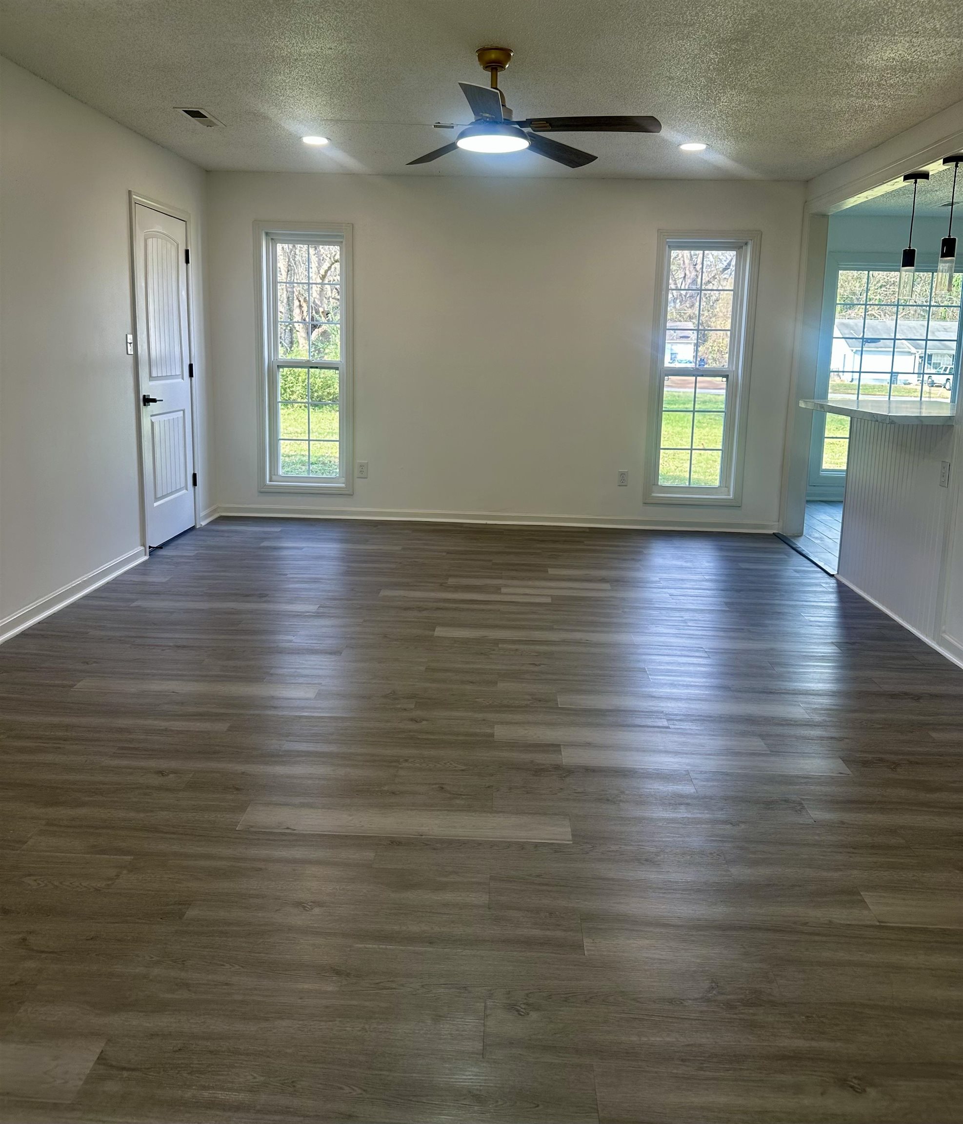 Unfurnished room with ceiling fan, dark wood-type flooring, and a textured ceiling