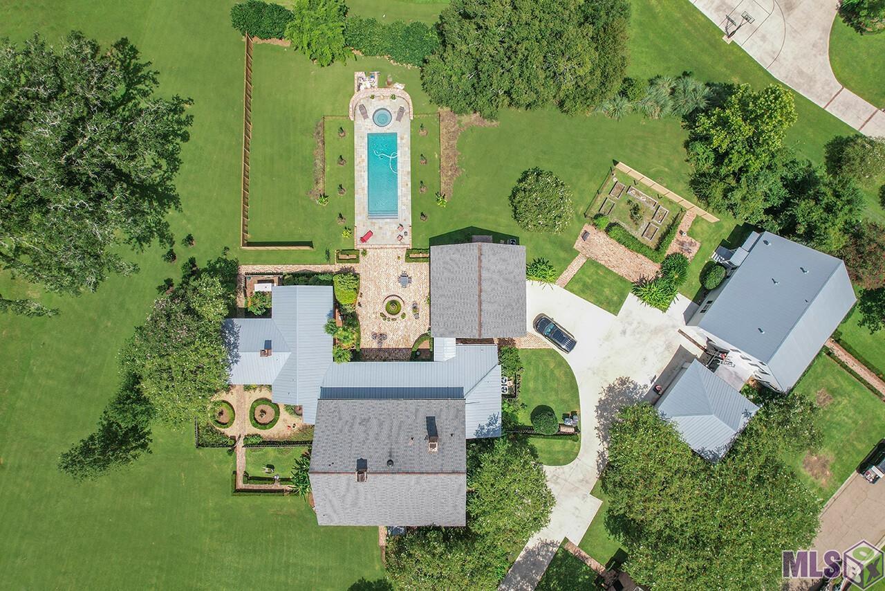 Spectacular & Secluded Estate in the prestigious gated community of St. Andrews! This custom built 4 Bedroom /3.5 Bath Home was designed by A Hays Town & located on a prime 2 acre lot surrounded by 250 year old live oaks laced w/ moss which creates Louisiana elegance.  A bit of history is now on the market in St. Andrews w/ this 1840 Vintage style home with a Caribbean influence that is featured in 2 of A Hays Town books as well as being listed in the Louisiana historical homes foundation.  This Estate was built in 1980 and Features: 4 Bedrooms, 3.5 Baths & another half bath w/ a shower off the laundry room & over 5,000 sq ft. of living area.  As you enter the front door you notice the grand foyer with old plantation wide plank heart of pine floors and a detailed staircase leading upstairs. The Louisiana style feeling of the home is evident in the old cypress ceiling, the large cypress beams and the handcrafted mantle surrounding the entire wood burning fireplace. Lots of natural light is created with the large wall of windows which overlook the covered porch area and the hot tub & gunite pool. These same bright windows carry into the breakfast & keeping area of the kitchen with the same warm woods and the “jumbo soft red” brick floors from a New Orleans convent that dates back to 1840 & features an additional wood burning fireplace! The master Suite has an adjacent office plus an additional fireplace & comes complete w/ large walk in closet. Upstairs there are 3 large bedrooms and 2 full baths. In addition to this living space they have added bedroom & bath above the garage that is perfect for a game room or student.   Also, on the grounds is a 2300 square foot guest cottage w/ old pine floors, 2 bedrooms, bonus room, kitchen, living & full 2 car garage designed by Andy McDonald.  A Pigeonnier on the property is used as a private chapel, designed by Al Jones. Another plus is a Generac generator that services the entire house and this home is not in a flood zone.