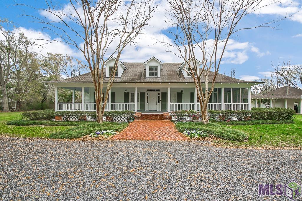 14 + acre  Southern Estate that is perfect for HORSES just moments from Baton Rouge in Ascension Parish on the HIGH SIDE of picturesque Bluff Road surrounded with legacy live oaks, pond, pool, barn, storage and a second 2 bedroom cottage. The large Acadian style home has 5 bedrooms (3 down) and 2 up for complete privacy and solitude. The Double Primary downstairs  bedrooms are conducive to generational living. The wrap around porch and partial screened porch invite you for endless views of the sunset. Antique beams, vaulted ceiling, many updates in kitchen and baths through the years.  There is a beautiful pool, pond with fountain, and a large recreation room over the barn  to make this your private sanctuary. NEVER FLOODED. The guest cottage was built in 2000 and is tucked across the walkable bridge , with woods and trails. It has 2 bedrooms ,one bath and wooden flooring throughout with a full kitchen which could be perfect family or rental income.