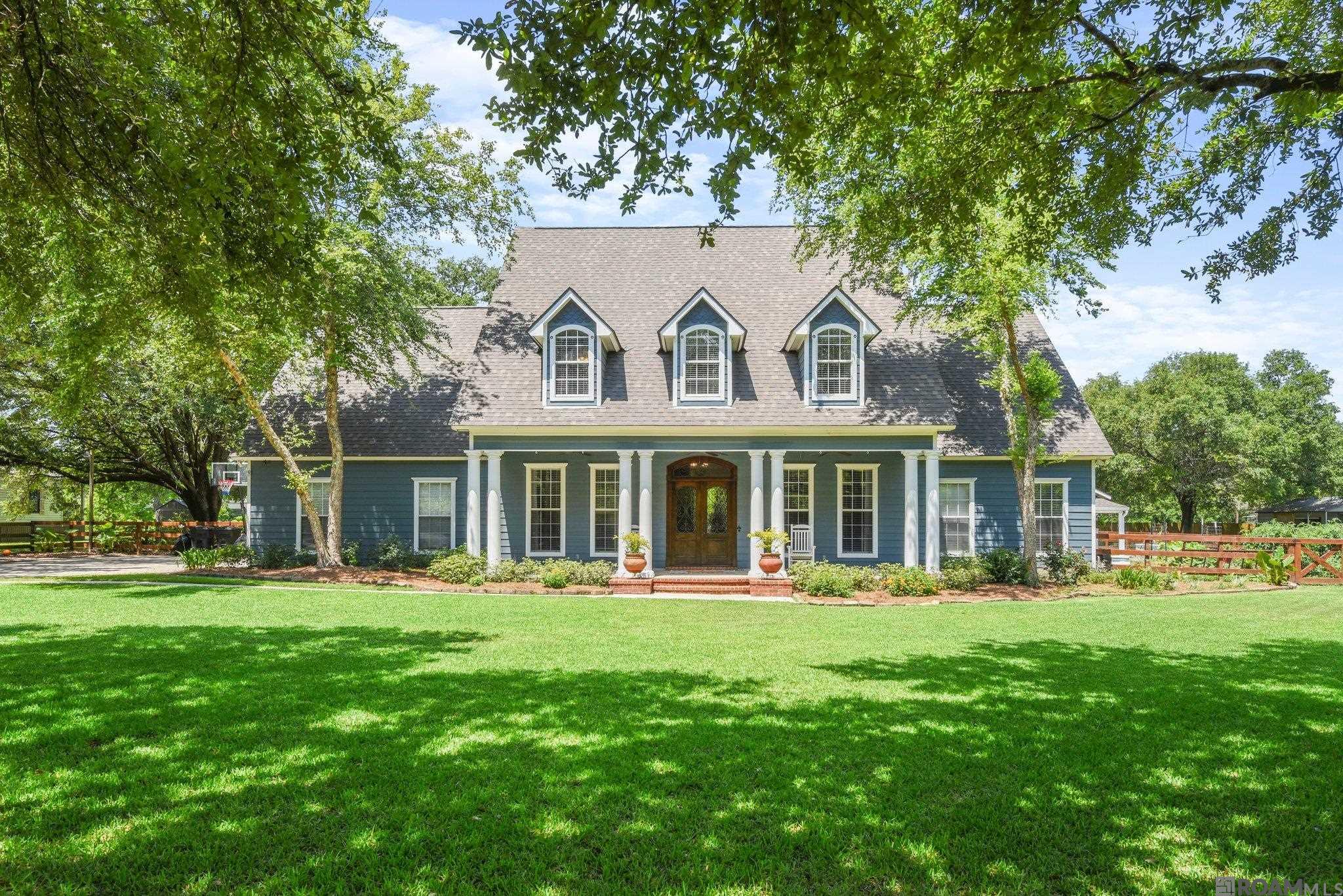 WOW... a TRUE MASTERPIECE HERE!! Ideal location and top ranked Dutchtown schools. Roof is only 3 years old.  Enjoy the oversized pool- just in time for summer! The curb appeal of this beauty is one you dream about- an Acadian style home with a front porch and a large private piece of property with Farm style fencing and mature Oak Trees. The property is nearly one acre.  Country living at it's finest- bring the chickens, there is a chicken coop! As you enter the grand foyer and are greeted with pine floors, there are oversized custom french doors to the Home Office. To the left is the dining area with a formal chandelier and swinging door to enter into the kitchen.  With 3 cm granite, brick flooring, stainless appliances, oversized sink, gas stove, huge pantry and two islands, this is a kitchen for a real chef.  The kitchen is open to the family room which is perfect for entertaining. There are ample built ins and a brick fireplace with wood beam mantle. Off of the den is the master suite. With wood floors and soft walls, this quaint room is the perfect retreat.  The master bathroom has his and her vanities with granite slab counters, separate soaking tub and shower and a great walk through closet with tons of storage space.  Upstairs are four huge bedrooms, all with great closet space, no carpet, two bathrooms, attic access, and more!!  The rooms are so large, you can even use one as a bonus/game room while still having three great bedrooms upstairs. With two sets of stairs to access the additional bedrooms, the kids can easily get to the laundry room which has two walls of cabinet storage!  The backyard is offers an 8’ fence and  bamboo across the back adding for extra privacy. The trees, well they are breathtaking!  The storage house or workshop has a precious front porch facing the gunite pool- you could even convert the workshop into a pool house, mother in law suite, etc the options are endless.  This home is truly exquisite! Schedule your showing today!!
