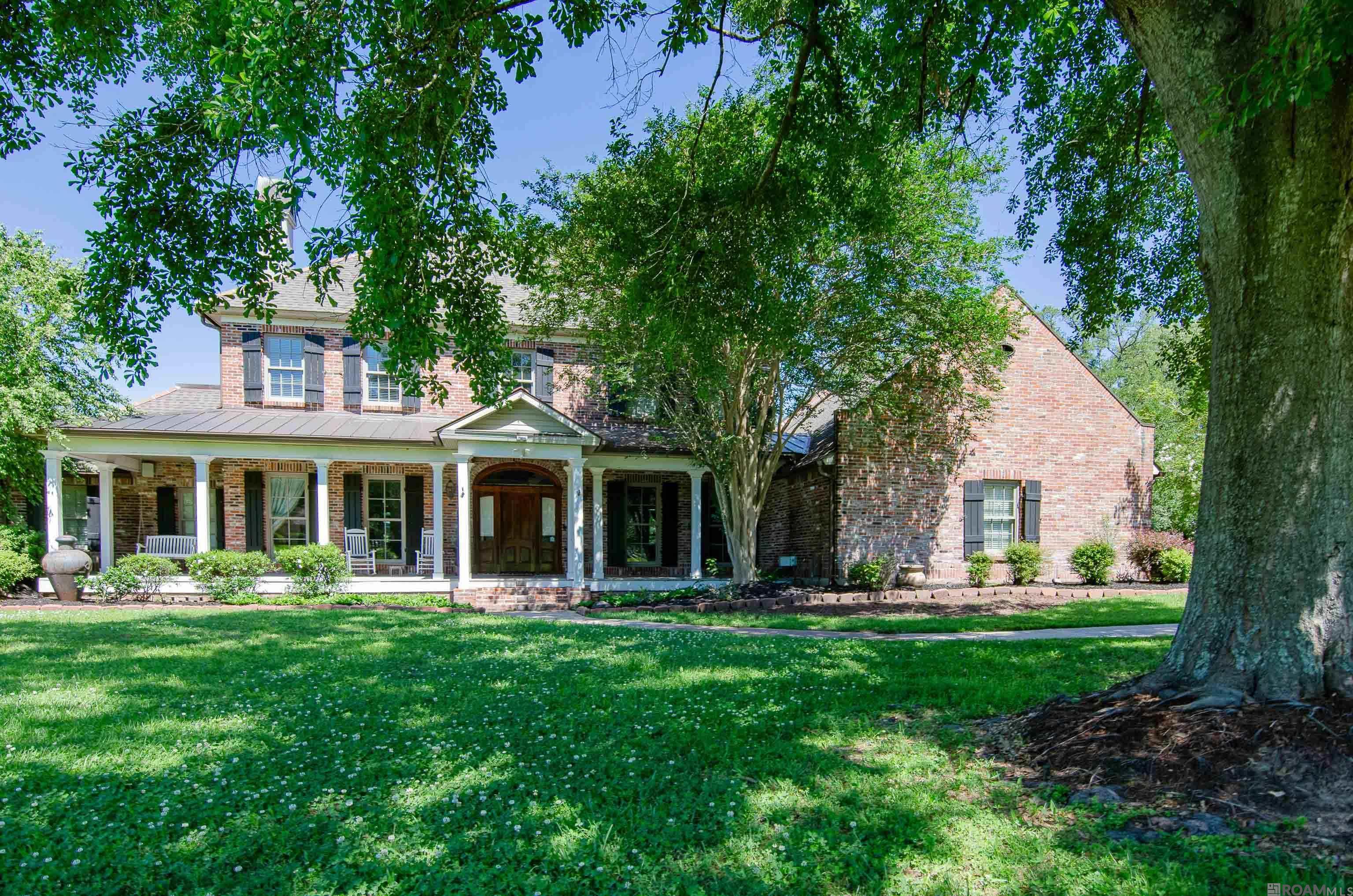 This home has it all!  Located in Prairieville in Manchac Plantation on an estate sized lot and on Bayou Manchac!  It is a Beautiful Acadian style home with plenty of porch space for sitting and enjoying the scenery.  The backyard boasts a gunite pool with waterfall, beautiful live oak trees and access to Historic Bayou Manchac. Inside you will find brick archway openings into the formal living and formal dining area.  The family room, kitchen and breakfast area are open concept making it a Great area to entertain. The kitchen offers stainless appliances including 6 burner gas stove, double oven, warming tray, ice maker, dishwasher, built in refrigerator and microwave  There is a designated office downstairs with a view of the backyard.  The primary bedroom and bathroom along with a secondary bedroom and bathroom are located downstairs. The primary bedroom has pine flooring with a sitting area, and the bathroom has separate tub and shower along with an oversized walk-in closet.  Upstairs you will find a split floorplan each side having 2 bedrooms sharing Jack-n-Jill bathrooms with a catwalk separating them. There is also an upstairs designated space currently used as a gym, but could be used for several things including game room.  It has a balcony overlooking the backyard. Outside there are 2 separate garage areas that park 3 cars and room for riding lawn mower.  There is also additional parking spaces making it easy for owners with many vehicles.  Don't miss this beautiful property