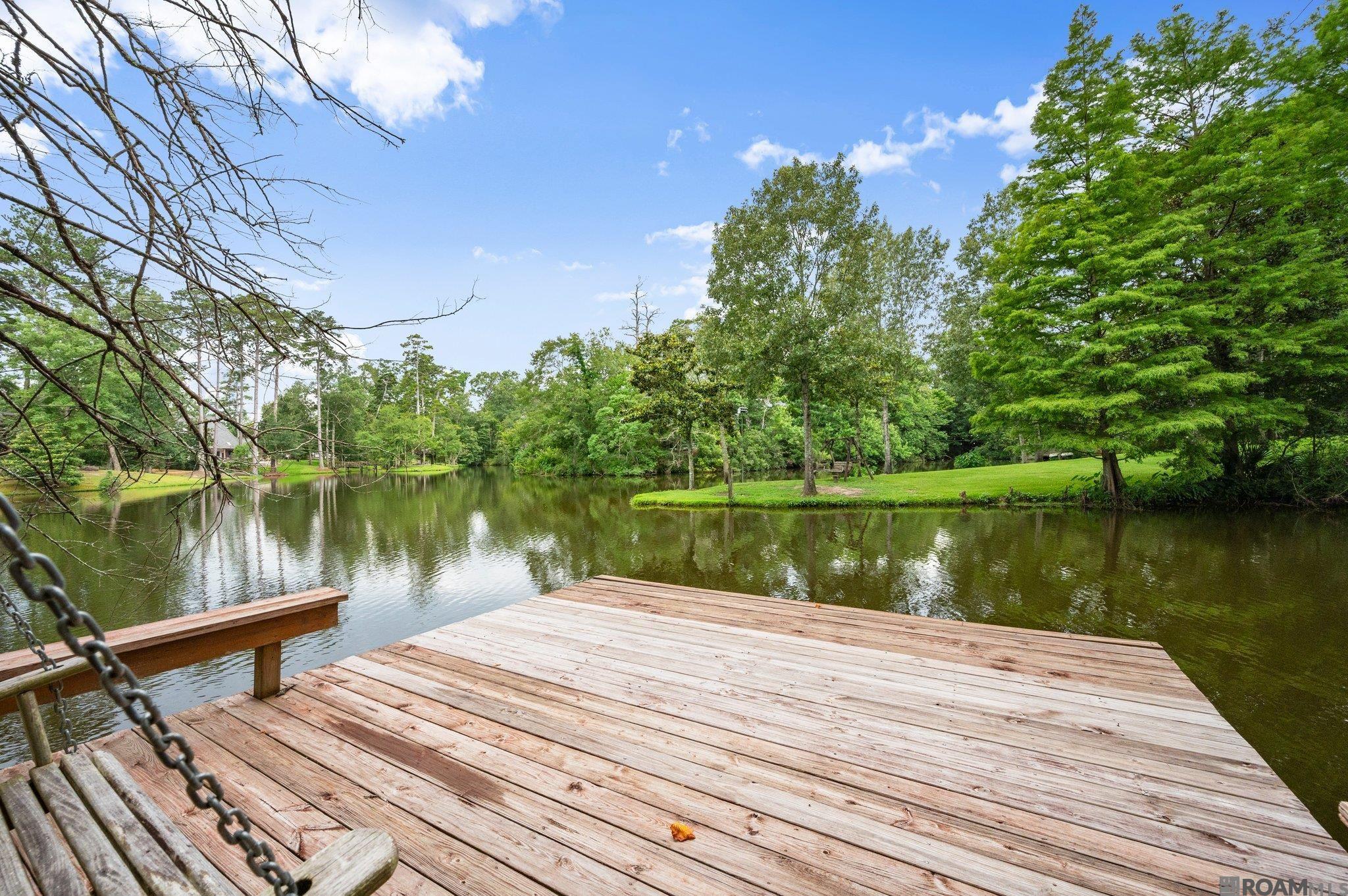 What an incredible view in The Lake at White Oak.  Enjoy your morning coffee, entertain your friends and family, fish off the dock, kayak and so much more in this private oasis! Lake views from almost every room in this 4 Bedroom, 3 Bath home.  The living room overlooks the patio and lake with a wall of windows.  There is a fireplace and built-ins along with a wet bar.  The kitchen has an abundance of cabinetry, double ovens, breakfast room, and the refrigerator remains.  Large picture window in the formal dining.  Split floor plan with primary bedroom having windows overlooking the lake!  It's a spacious bedroom with a sitting area, two walk in closets with built in cabinets, his/her vanities, water closet, jetted tub, and separate shower.  The additional bedroom overlooks the lake and has a wall of built-in cabinets.  Updated hall bath with a tiled shower.  Two additional bedrooms on the second floor share an updated bathroom.  Fully landscaped, gutters. whole home generator, two car garage and additional storage room.  Located on a quiet cul-de-sac with a large lot, walkway and dock with with a swing.  Convenient to schools, shopping, restaurants, entertainment, I-10 and I-12.