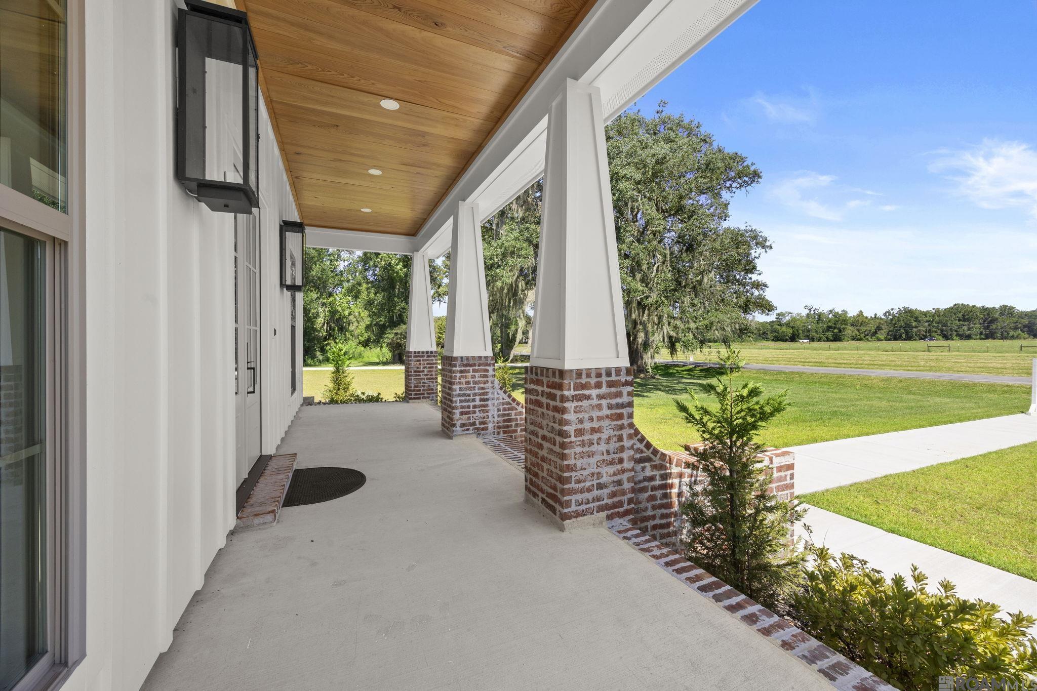 This exceptional custom-built home by TC Construction offers refined luxury on 1.36 beautifully landscaped acres in a private, gated community. Framed by stately live oaks and lush green sod, the exterior sets a tranquil tone for what awaits inside. Step through the front door into a stunning interior crafted with timeless detail by The Old Mill. White oak flooring, custom ceiling-height cabinetry, and architectural millwork elevate every space. The welcoming foyer leads into a soaring living room with a 15-foot vaulted ceiling, honed marble fireplace, and a show-stopping white oak herringbone feature that rises to the ceiling. Flanking French doors flood the space with natural light and open to an expansive patio. The open-concept kitchen is a chef’s dream—featuring quartzite countertops, a 6-burner gas range with pot filler, custom vent hood, and white oak cabinetry. A large island with built-in microwave and designer lighting anchors the space, while the breakfast area offers a cozy spot for casual meals. A walk-in pantry with custom shelving and sliding white oak doors, plus an ice maker, complete the kitchen’s impressive functionality. The primary suite is a private retreat with spa-like amenities: a luxurious soaking tub, oversized walk-in shower with dual shower heads, heated mirrors, custom lighting, and a separate water closet with heated toilet. The walk-in closet is designed for both beauty and function, with built-in storage, shelves, and lighted display cubbies. Two additional bedrooms are connected by a Jack-and-Jill bath, while a fourth bedroom offers flexibility as a guest room or home office. Outdoors, the spacious back patio features custom wood plank ceilings and overlooks a large yard—perfect for entertaining or unwinding in peace. This thoughtfully designed home combines elegance, comfort, and craftsmanship in every square foot. A must-see for discerning buyers.