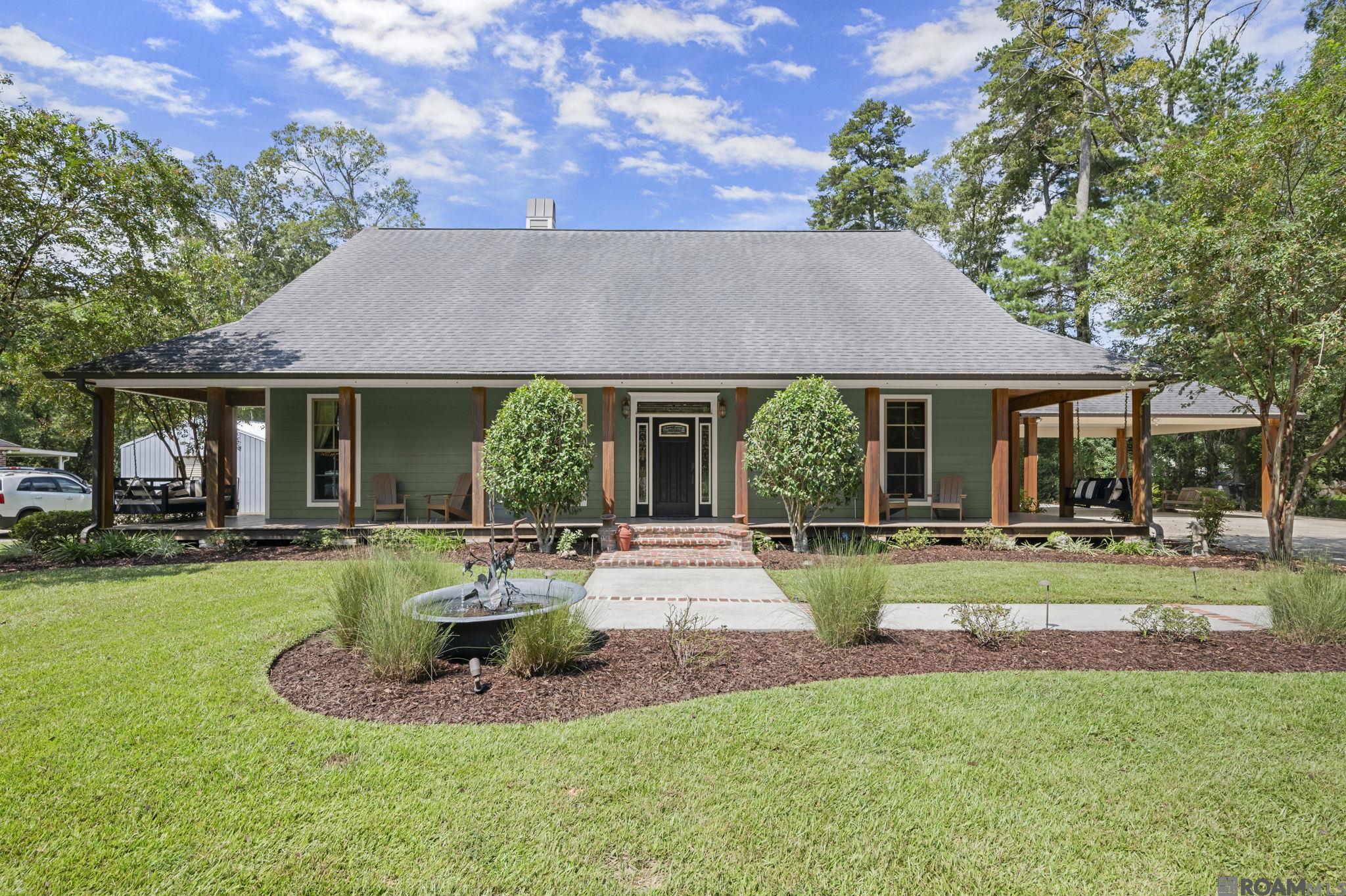 Beautiful, custom built 3 bedroom, 3 bath home with an office that sits on just over one & a quarter acre lot. Open floor plan that is perfect for entertaining. 9 foot ceilings and wood floors throughout living areas. Kitchen features granite countertops, custom built cypress cabinets, walk-in pantry, large island, gas stove, double ovens, stainless steel appliances, and a wine fridge. One of the biggest primary bedrooms you'll see with a en-suite with dual vanities, separate shower, and soaking tub. You can enjoy owning a piece of LSU history with the wood floors in the 2 additional bedrooms being reclaimed wood from the original Alex Box stadium! Flooring was added to the attic and there is additional storage space above the carport. Enjoy outdoor living with an inviting wrap around porch in the front of the house and a screened porch in the back. Feel right at home on the outdoor patio with its fireplace, pergola and a wonderful view of the pond. Along with the home having a whole house generator, there is also a detached 20x30 shop with electricity plus additional enclosed storage areas. Home did NOT flood.