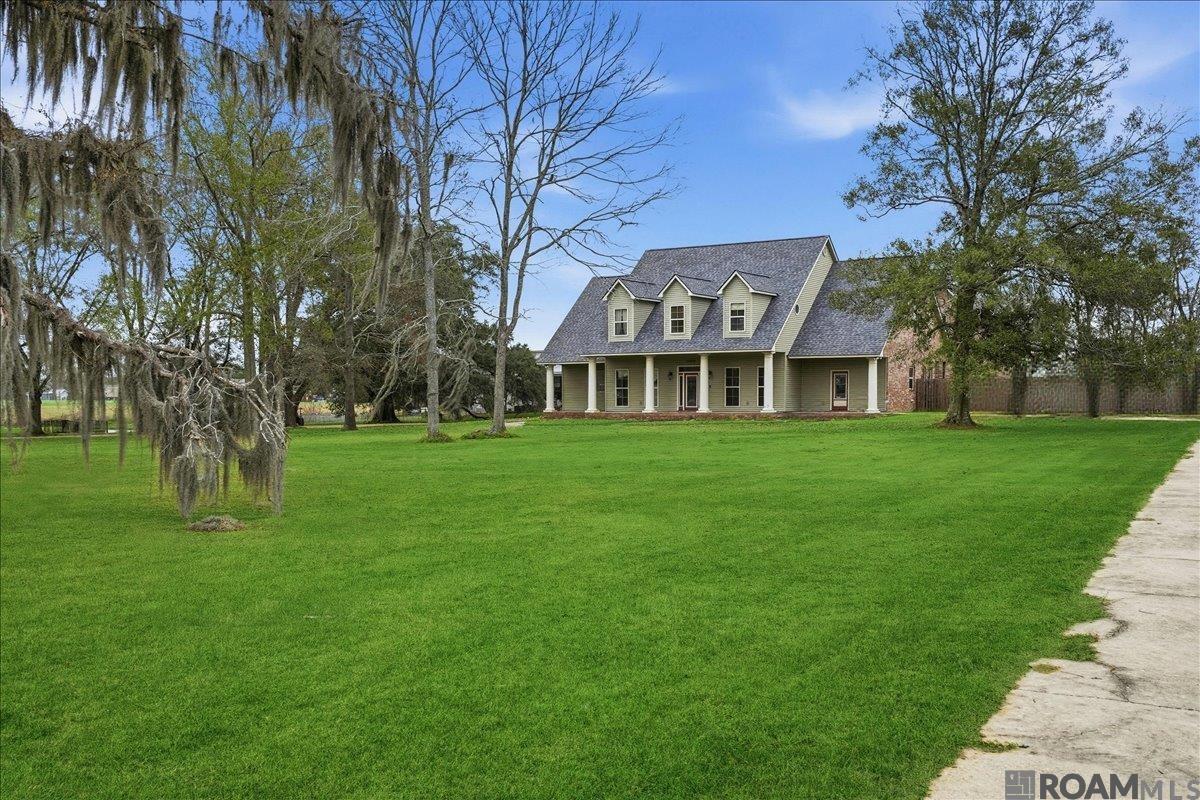 This custom-built Acadian-style home is a rare find, offering both luxury and comfort. With 5 spacious bedrooms, 3.5 bathrooms, an office and an additional 15x21 recreation room that could easily serve as a 6th bedroom, this home is designed for both relaxation and entertainment. Set on 1.91 acres of beautifully landscaped grounds, the main house offers 3,817 sq ft of living space. The resort-style backyard features a covered patio, wiring for a outside jacuzzi tub, a stunning saltwater gunite in-ground pool complete with 2 small waterfalls, a slide, tanning ledge, water fill regulator, fiber optic lighting, and depths ranging from 3ft to 9ft. The primary bath is a luxurious retreat with a custom marble shower, Kohler programmable shower fixtures, a Jacuzzi bubble tub, granite countertops, and a double vanity with sleek glass sinks. Upon entry, you'll be welcomed by a grand foyer with a large black chandelier, which can be lowered remotely for easy cleaning. The gourmet kitchen is equipped with stainless steel appliances, including a 5-burner gas stove with a vented hood, granite countertops, and a deep sink with dual garbage disposals. Thoughtful storage solutions are found throughout the home, including slide-out baskets in all lower cabinets. The home features Luxury Vinyl Plank, ceramic, and carpet flooring, energy-efficient fold-in windows, high-boy toilets, and a beautiful wooden staircase.  Above the carport, you'll find a 678 sq ft guest apartment, offering ultimate privacy. The outside garage storage room is  currently being used as a weight/workout room. The apartment includes a kitchenette with a granite bar with sink, dishwasher, a living room, a bedroom, a separate bathroom, and a balcony with a view of the pool ***ATTENTION! DON'T GO ONTO THE GARAGE APARTMENT BALCONY. SOME FLOOR PLANKS/BOARDS MIGHT BE AGED AND GIVE WAY.*** Schedule your private showing today!